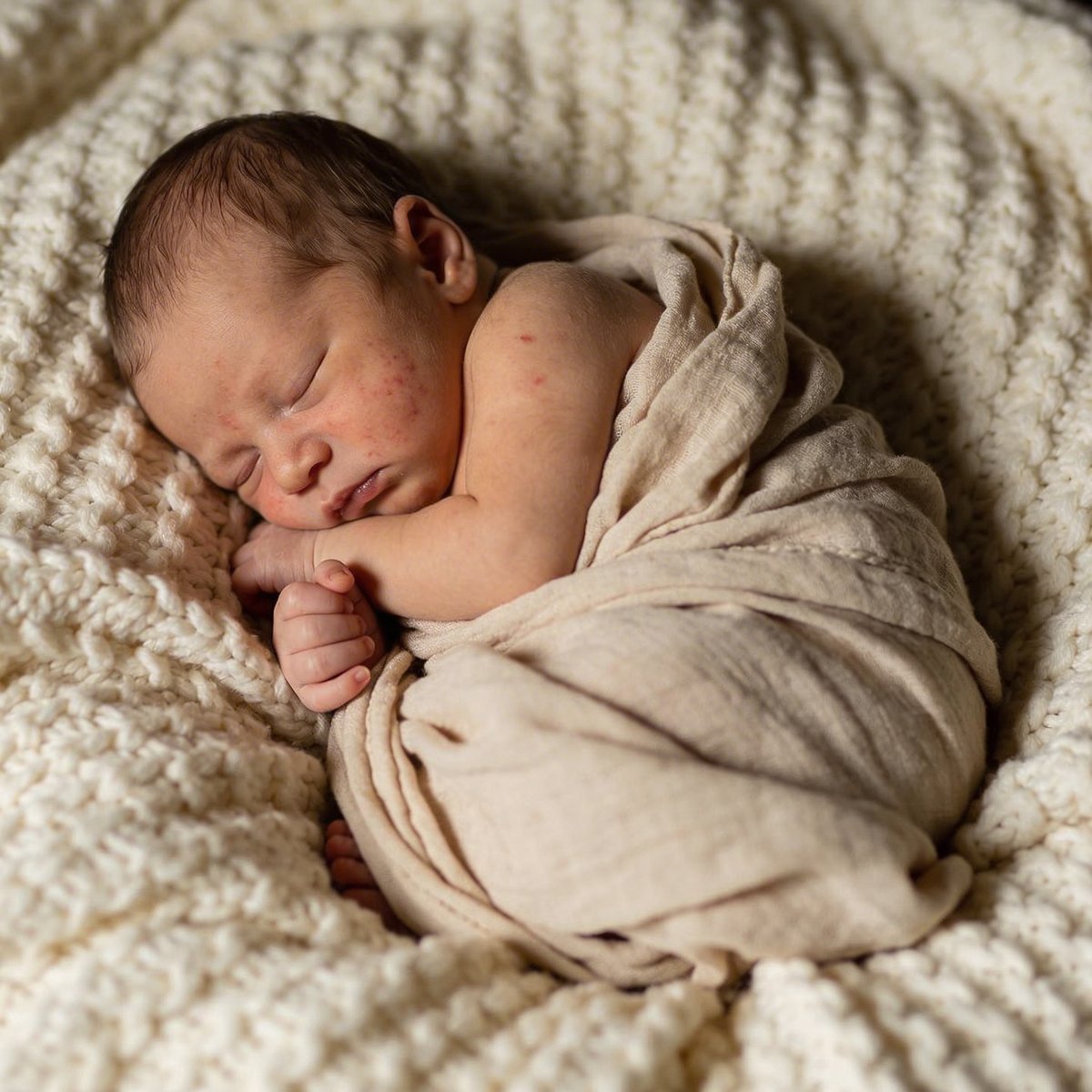 Österreichisches Neugeborenes in einer weichen Wickelpose, fotografiert in der ersten Lebenswoche in einem gemütlichen Studio